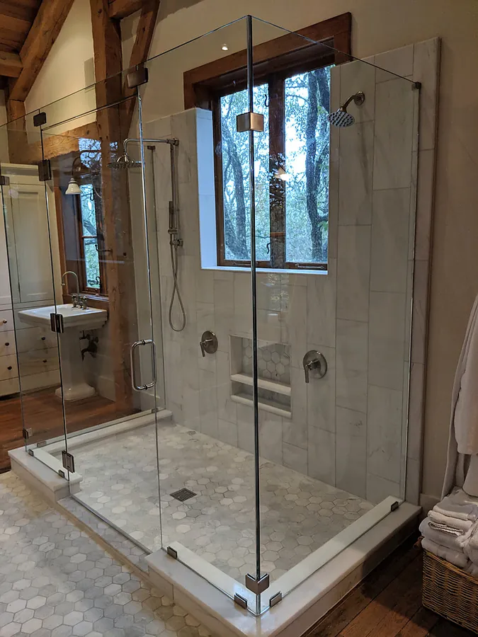 Stone and glass detailing in a spacious bathroom.