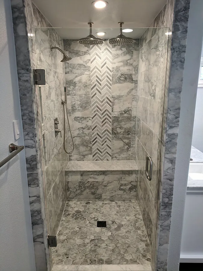 A walk-in shower with a herringbone tile focal wall.