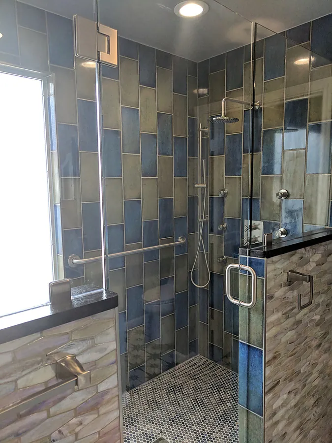 Geometric tile with clear glass shower panels.