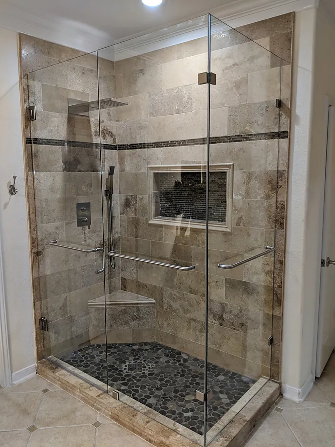 A glass-enclosed shower with contrasting stone textures.