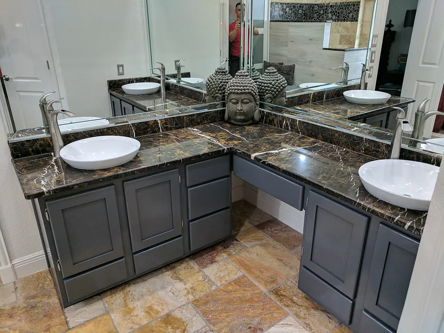 A double vanity with dark countertop and stone accent walls.