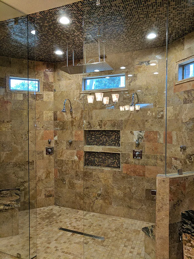 A spacious glass enclosure with warm-toned stonework.