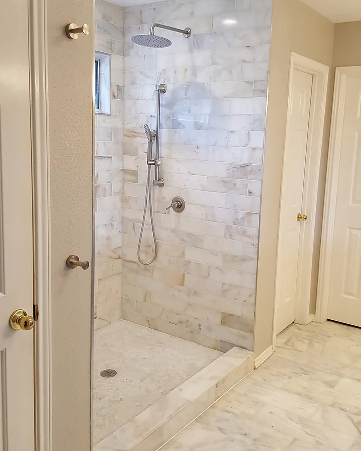 Light marble-look tile and a minimalist open shower design.