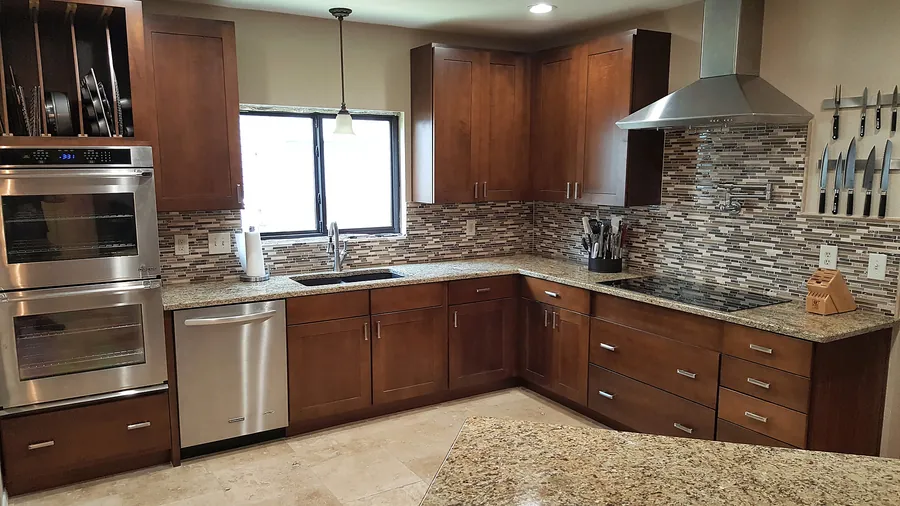 Wood cabinetry, stone countertops and layered backsplash details.