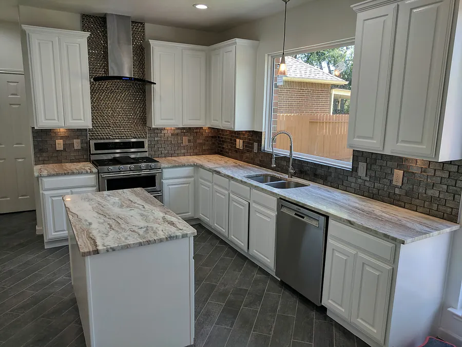 White cabinetry, detailed backsplash, and an expansive island.