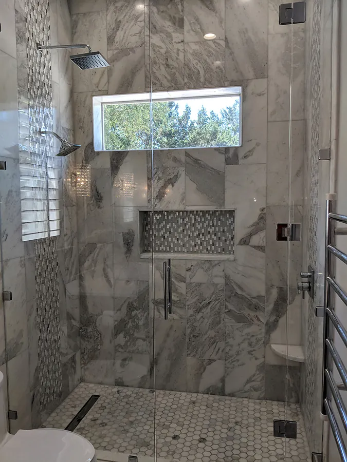 A walk-in shower finished with patterned stone-look tile.