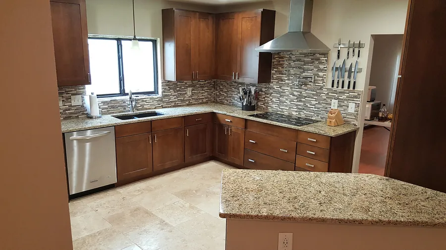 Natural wood kitchen with stone-look flooring and backsplash.