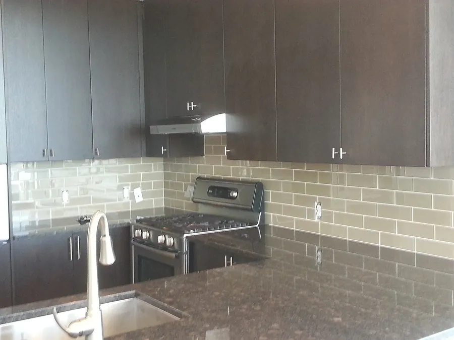 Dark cabinets with light tile backsplash and stainless steel.