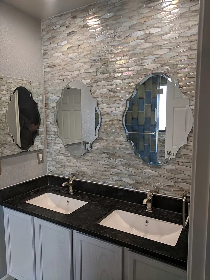 Stone accent wall with distinctive mirrors and dark countertops.